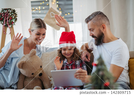 Family making Christmas video call with relatives during holiday celebration at home. Family making Christmas video call with relatives during holiday celebration at home. 142809715