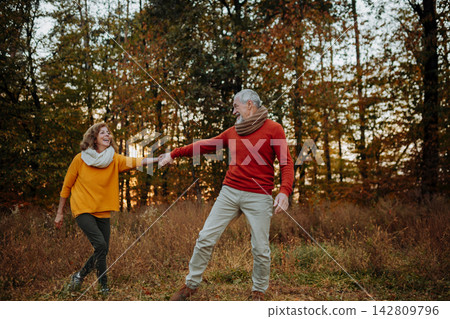 Older couple holding hands in autumn nature. 142809796