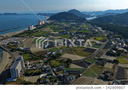 空拍照片顯示了德島縣鳴門市的沿海地區、田野、居民區和山脈。 142809807