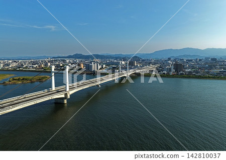 An aerial photograph capturing a cable-stayed bridge and the Yoshino River riverbed in Tokushima City, Tokushima Prefecture. An aerial photograph capturing a cable-stayed bridge and the Yoshino River riverbed in Tokushima City, Tokushima Prefecture. 142810037