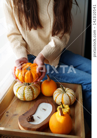 Child hands holding small orange pumpkin by autumn decor tray Child hands holding small orange pumpkin by autumn decor tray 142810541