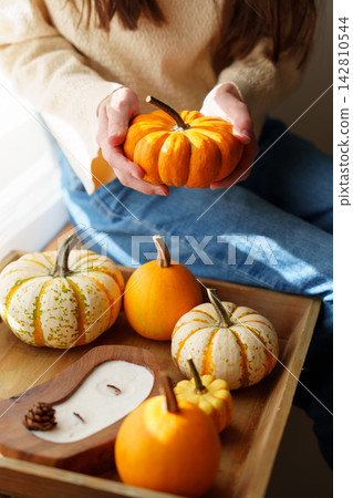 Child hands holding small orange pumpkin by autumn decor tray Child hands holding small orange pumpkin by autumn decor tray 142810544