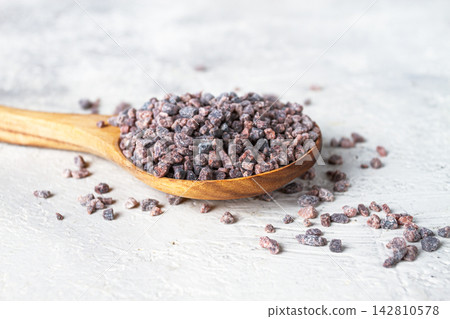 Crystals of black salt, on a wooden spoon, on a light surface, top view, Crystals of black salt, on a wooden spoon, on a light surface, top view, 142810578