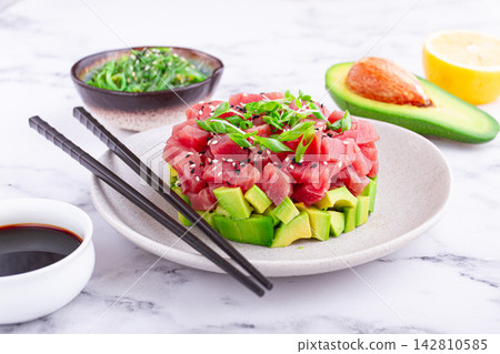 Fresh tuna tartare with avocado served on a marble table with soy sauce and seaweed salad Fresh tuna tartare with avocado served on a marble table with soy sauce and seaweed salad 142810585