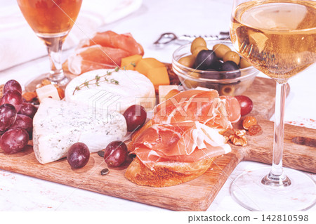 Cheese and charcuterie board with wine and grapes at a casual gathering, no people, Cheese and charcuterie board with wine and grapes at a casual gathering, no people, 142810598