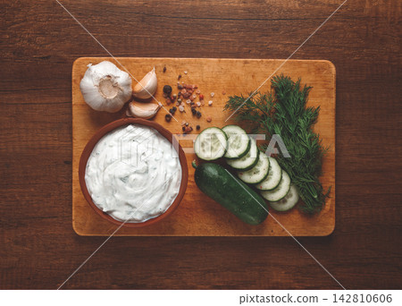 Greek zajiki sauce, in a clay bowl, on a wooden board, with ingredients, top view, no people, 142810606