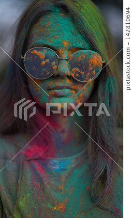 Portrait of girl standing being covered in coloured powder at holi festival Portrait of girl standing being covered in coloured powder at holi festival 142810694