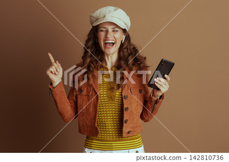 Excited Woman Pointing Up While Using Smartphone Excited Woman Pointing Up While Using Smartphone 142810736