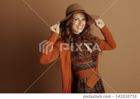 Chic Woman Holding Hat Brim with Cheerful Smile Chic Woman Holding Hat Brim with Cheerful Smile 142810738