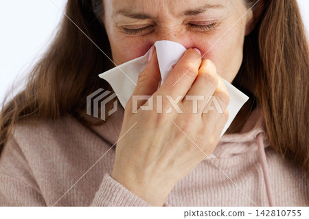 Woman Blowing Nose with Tissue During Illness Woman Blowing Nose with Tissue During Illness 142810755