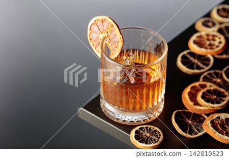 Old-fashioned cocktail with ice and a dried orange slice. Old-fashioned cocktail with ice and a dried orange slice. 142810823