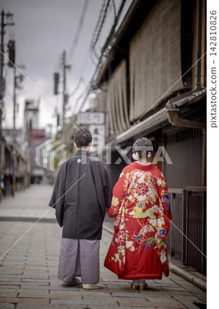 A bride and groom in elegant traditional Japanese attire walk through the streets of Kyoto. A bride and groom in elegant traditional Japanese attire walk through the streets of Kyoto. 142810826