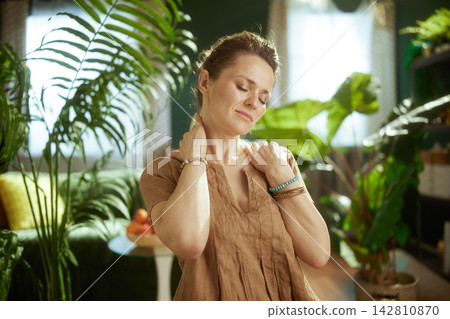 Woman Massaging Neck for Tension Relief in Cozy Home Woman Massaging Neck for Tension Relief in Cozy Home 142810870
