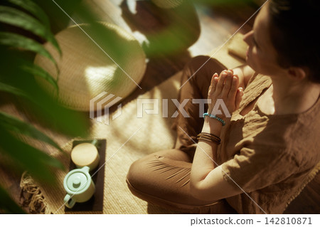 Woman Meditating in Prayer Pose at Home 142810871