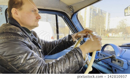 Male driver riding on blue vintage auto at city road on sunny day. Serious man driving retro vehicle at urban street. Confident guy moving in his old auto on route. Slow motion Male driver riding on blue vintage auto at city road on sunny day. Serious man driving retro vehicle at urban street. Confident guy moving in his old auto on route. Slow motion 142810937