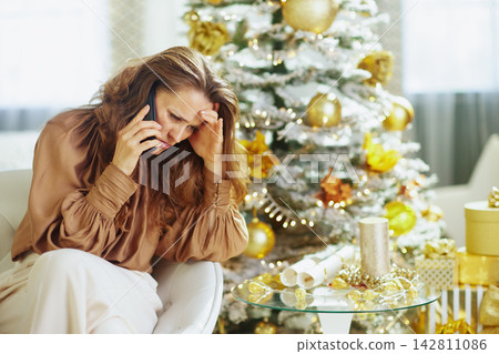 Distressed Woman on Phone by Christmas Tree Distressed Woman on Phone by Christmas Tree 142811086