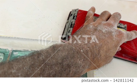 Male hand uses brush to clean finished wall surface removing dust and small imperfections after renovation work. Young worker carefully prepare smooth wall for next finishing stage inside room. POV Male hand uses brush to clean finished wall surface removing dust and small imperfections after renovation work. Young worker carefully prepare smooth wall for next finishing stage inside room. POV 142811142