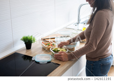 Person preparing healthy meals in glass containers at home Person preparing healthy meals in glass containers at home 142811191