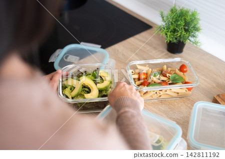 Person preparing healthy meals in glass containers at home Person preparing healthy meals in glass containers at home 142811192