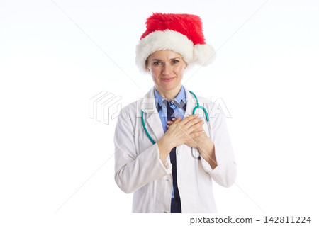 Friendly Female Doctor in Santa Hat with Hands on Chest Friendly Female Doctor in Santa Hat with Hands on Chest 142811224