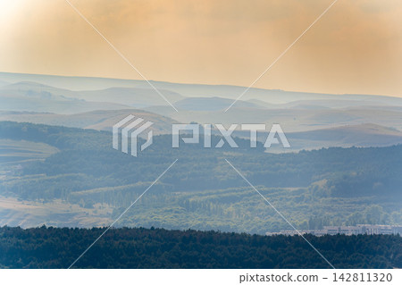 Layers of green mountains and hills in the haze during sunset. Panoramic View of Green hills and Meadow. Layers of green mountains and hills in the haze during sunset. Panoramic View of Green hills and Meadow. 142811320