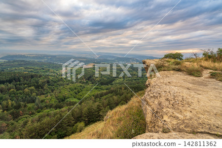 Majestic rocky cliffs and towering trees against blue sky. View of the rocks in Kislovodsk, Russia. Majestic rocky cliffs and towering trees against blue sky. View of the rocks in Kislovodsk, Russia. 142811362