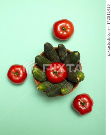 Ripe tomatoes and cucumbers on a green background Ripe tomatoes and cucumbers on a green background 142811419