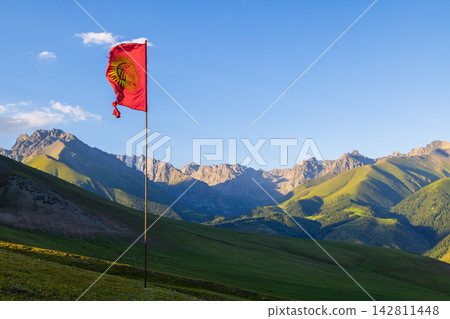 Kyrgyzstan valley with tattered national flag and mountain range 142811448
