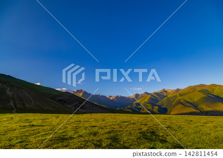 Majestic mountains at sunset over grassy plains in Kyrgyzstan Majestic mountains at sunset over grassy plains in Kyrgyzstan 142811454