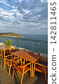 Rooftop Cafe Wooden Table and Chairs with Scenic Ocean View and Partly Cloudy Sky 142811465