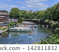 Narrowboats moored in London's canals and people enjoying stand-up paddleboarding (SUP). 142811832