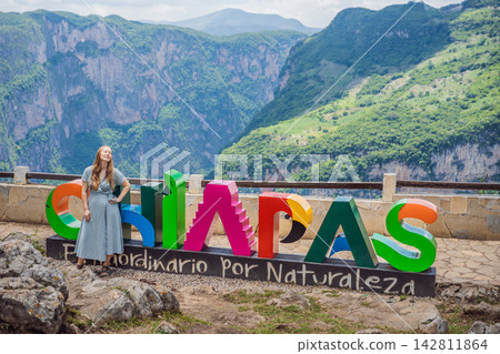 Woman tourist at Sumidero Canyon viewpoint in Chiapas Mexico beside Spanish sign Chiapas, Extraordinario por naturaleza meaning Chiapas, extraordinary by nature. Woman tourist at Sumidero Canyon viewpoint in Chiapas Mexico beside Spanish sign Chiapas, Extraordinario por naturaleza meaning Chiapas, extraordinary by nature. 142811864