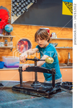 Boy experimenting with hands on science activity in a learning space indoors with interactive equipment STEM education curiosity creative play concentration and side view. Boy experimenting with hands on science activity in a learning space indoors with interactive equipment STEM education curiosity creative play concentration and side view. 142812012