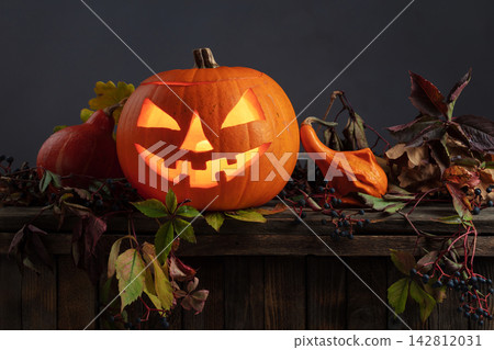 Halloween pumpkin head jack lantern with dried-up leaves. Halloween pumpkin head jack lantern with dried-up leaves. 142812031