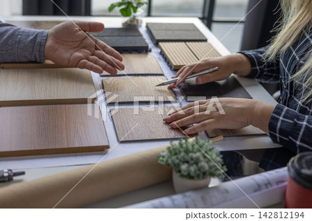 Interior design teamwork cooperates on selecting variety of wood-textured samples for flooring or furniture materials. Interior design teamwork cooperates on selecting variety of wood-textured samples for flooring or furniture materials. 142812194