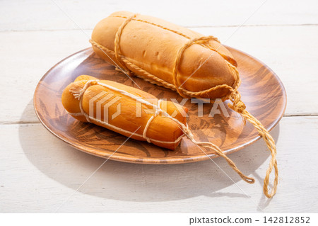 Provolone cheese, some smoked provolone cheeses made in Brazil placed on a ceramic plate, on rustic white wood, selective focus. Provolone cheese, some smoked provolone cheeses made in Brazil placed on a ceramic plate, on rustic white wood, selective focus. 142812852