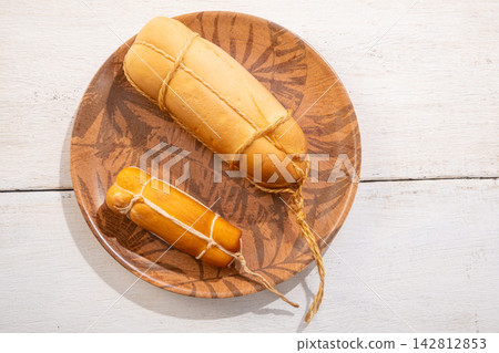 Provolone cheese, some smoked provolone cheeses made in Brazil placed on a ceramic plate, on rustic white wood, selective focus. Provolone cheese, some smoked provolone cheeses made in Brazil placed on a ceramic plate, on rustic white wood, selective focus. 142812853