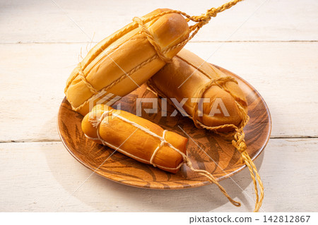 Provolone cheese, some smoked provolone cheeses made in Brazil placed on a ceramic plate, on rustic white wood, selective focus. Provolone cheese, some smoked provolone cheeses made in Brazil placed on a ceramic plate, on rustic white wood, selective focus. 142812867