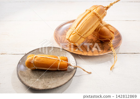 Provolone cheese, some smoked provolone cheeses made in Brazil placed on a ceramic plate, on rustic white wood, selective focus. Provolone cheese, some smoked provolone cheeses made in Brazil placed on a ceramic plate, on rustic white wood, selective focus. 142812869