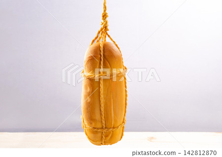 Provolone cheese, some smoked provolone cheeses made in Brazil hanging from ropes, white background, selective focus. Provolone cheese, some smoked provolone cheeses made in Brazil hanging from ropes, white background, selective focus. 142812870