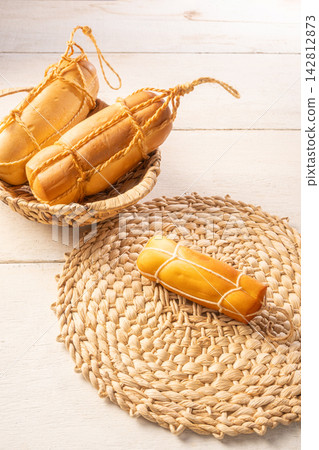 Provolone cheese, Some smoked provolone cheeses made in Brazil placed on straw utensils, on rustic white wood, selective focus. Provolone cheese, Some smoked provolone cheeses made in Brazil placed on straw utensils, on rustic white wood, selective focus. 142812873