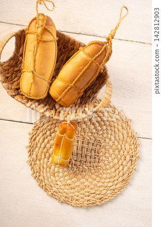 Provolone cheese, Some smoked provolone cheeses made in Brazil placed on straw utensils, on rustic white wood, selective focus. Provolone cheese, Some smoked provolone cheeses made in Brazil placed on straw utensils, on rustic white wood, selective focus. 142812903