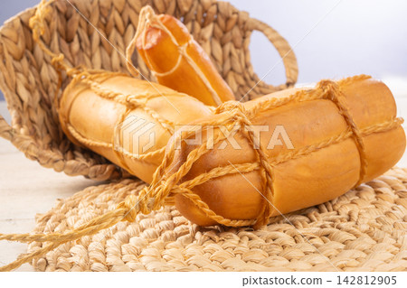Provolone cheese, Some smoked provolone cheeses made in Brazil placed on straw utensils, on rustic white wood, selective focus. Provolone cheese, Some smoked provolone cheeses made in Brazil placed on straw utensils, on rustic white wood, selective focus. 142812905