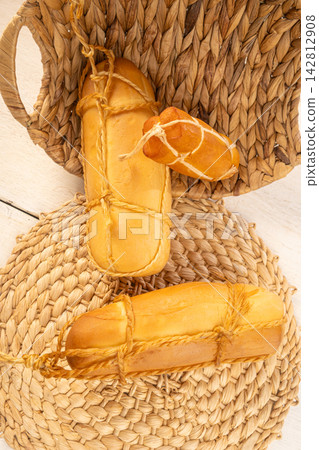 Provolone cheese, Some smoked provolone cheeses made in Brazil placed on straw utensils, on rustic white wood, selective focus. Provolone cheese, Some smoked provolone cheeses made in Brazil placed on straw utensils, on rustic white wood, selective focus. 142812908