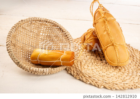 Provolone cheese, Some smoked provolone cheeses made in Brazil placed on straw utensils, on rustic white wood, selective focus. Provolone cheese, Some smoked provolone cheeses made in Brazil placed on straw utensils, on rustic white wood, selective focus. 142812910