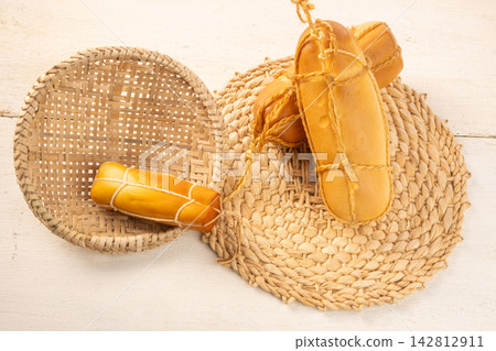Provolone cheese, Some smoked provolone cheeses made in Brazil placed on straw utensils, on rustic white wood, selective focus. Provolone cheese, Some smoked provolone cheeses made in Brazil placed on straw utensils, on rustic white wood, selective focus. 142812911
