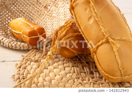 Provolone cheese, Some smoked provolone cheeses made in Brazil placed on straw utensils, on rustic white wood, selective focus. Provolone cheese, Some smoked provolone cheeses made in Brazil placed on straw utensils, on rustic white wood, selective focus. 142812943