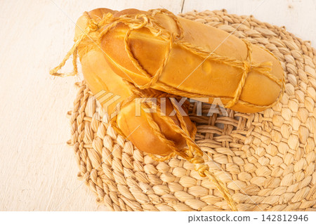 Provolone cheese, Some smoked provolone cheeses made in Brazil placed on straw utensils, on rustic white wood, selective focus. Provolone cheese, Some smoked provolone cheeses made in Brazil placed on straw utensils, on rustic white wood, selective focus. 142812946