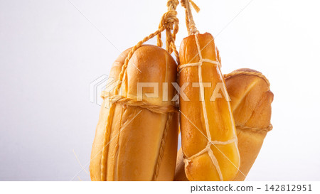 Provolone cheese, some smoked provolone cheeses made in Brazil hanging from ropes, white background, selective focus. Provolone cheese, some smoked provolone cheeses made in Brazil hanging from ropes, white background, selective focus. 142812951