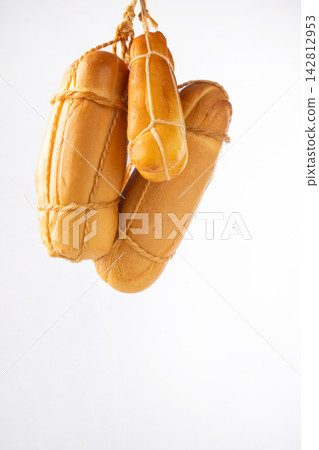 Provolone cheese, some smoked provolone cheeses made in Brazil hanging from ropes, white background, selective focus. Provolone cheese, some smoked provolone cheeses made in Brazil hanging from ropes, white background, selective focus. 142812953